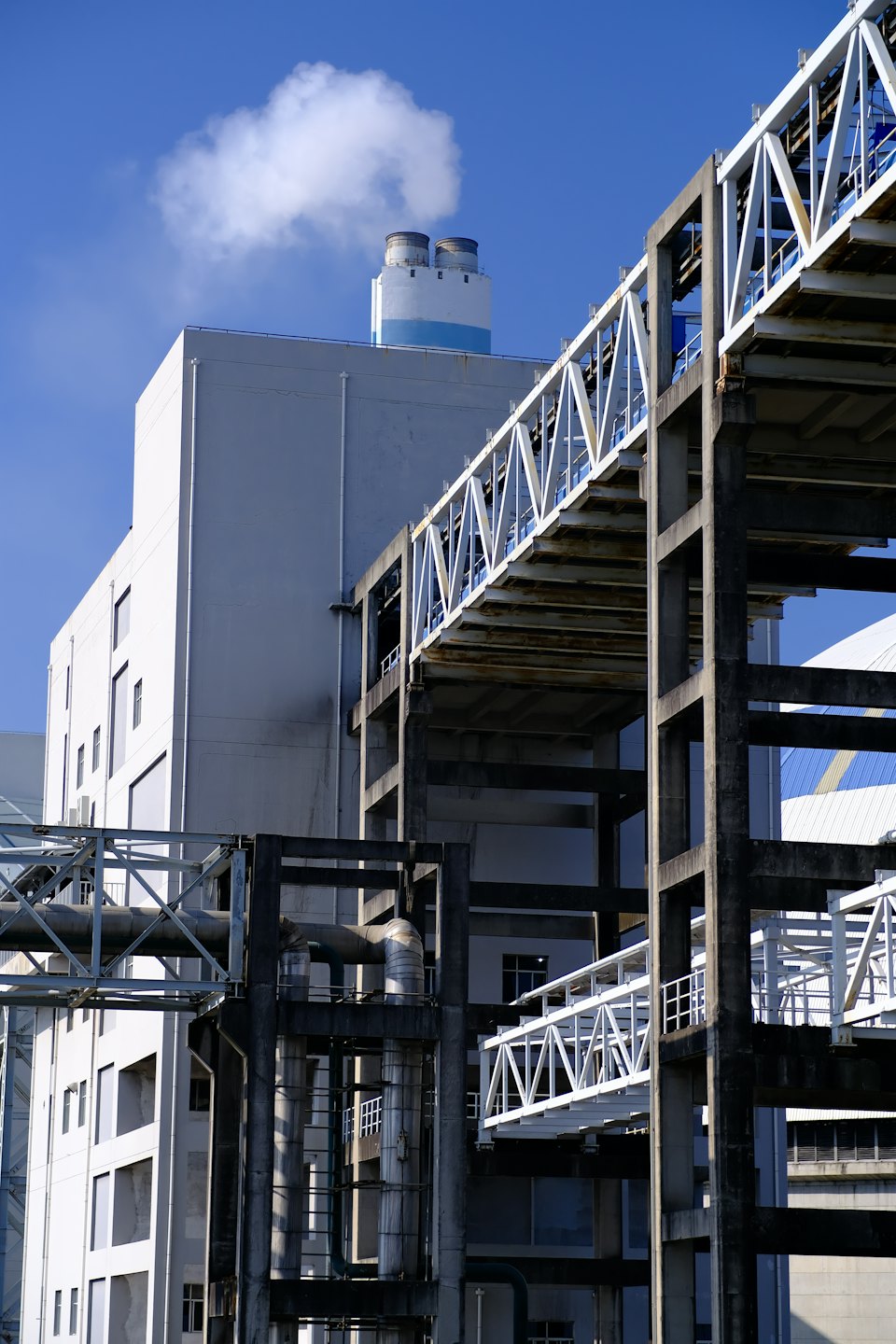 Stabilimento industriale con un camino fumante sotto un cielo blu.