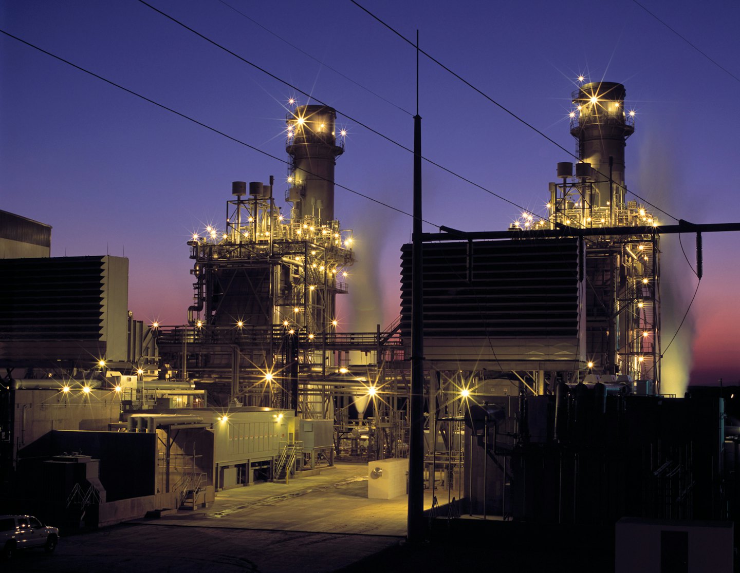 Centrale elettrica industriale al tramonto con vapore dagli scarichi.