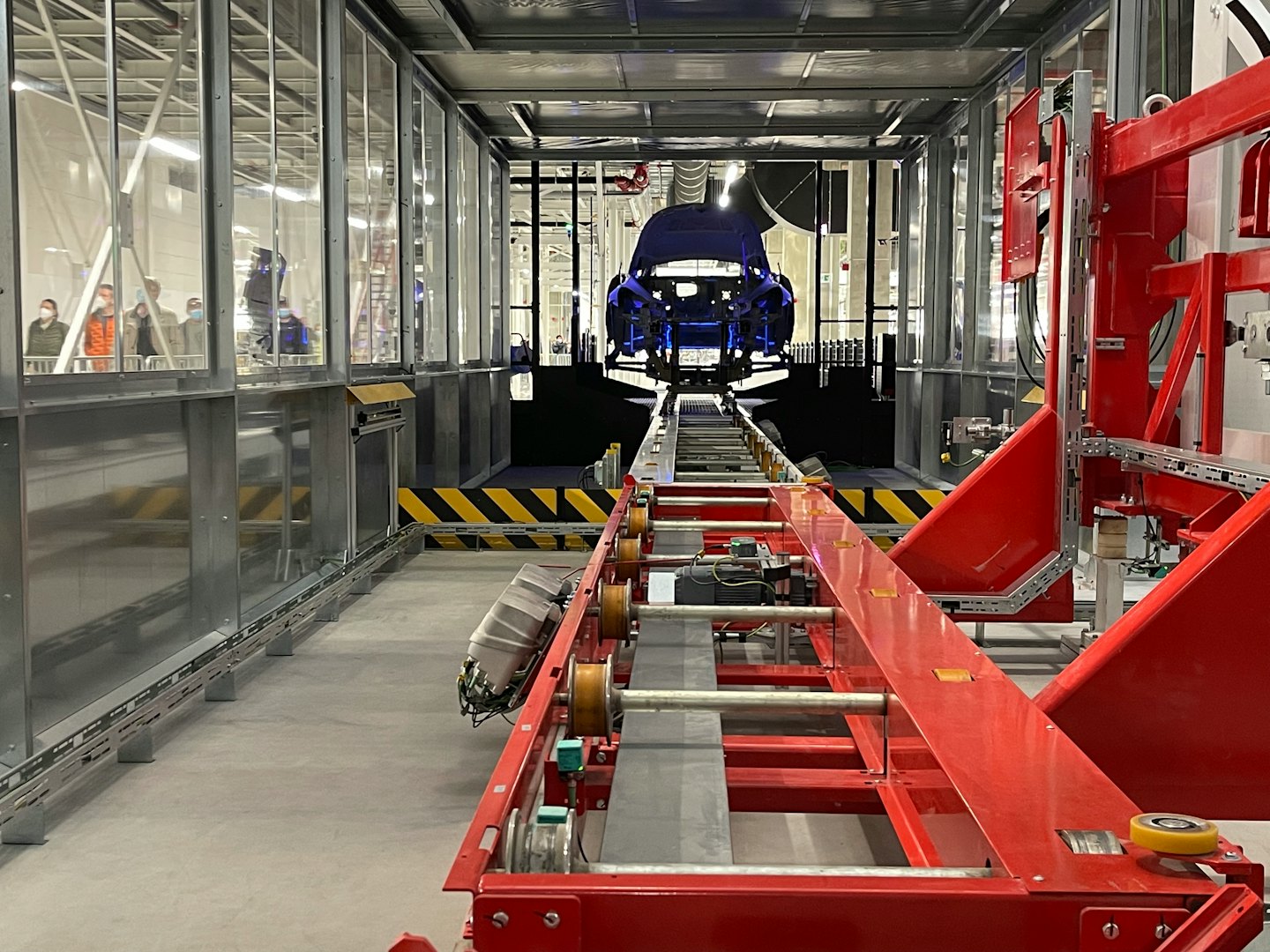 Telaio di un'auto blu in catena di montaggio con braccio robotico.