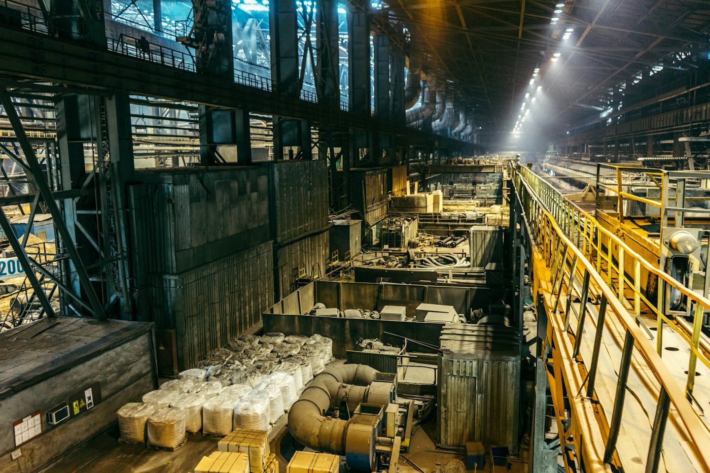 Interno di un affollato impianto di produzione industriale con macchinari e tubi.
