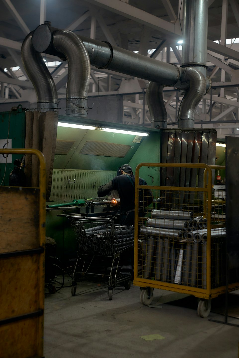 Operaio con elmetto smeriglia metallo in una fabbrica.